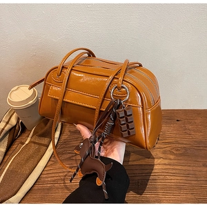 Caramel brown PU leather Boston bag with chocolate and dachshund pendants in autumn setting