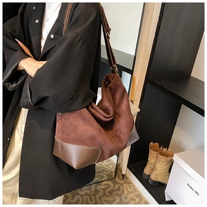 Detail of brown large shoulder bag featuring matte suede texture and contrast stitching