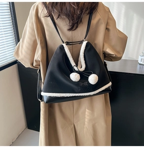 Detail of black PU crossbody bag featuring white fleece trim and cute pompom charms