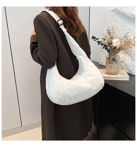 Détail du sac hobo blanc matelassé avec une large bandoulière réglable et texture douce