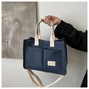 Navy blue canvas tote bag showing two front pockets and adjustable shoulder strap detail