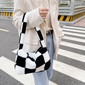 Detail of black and white checkerboard faux fur handbag carried by a model outdoors