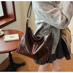 Sac hobo en cuir PU marron foncé brillant présenté dans un décor automnal élégant
