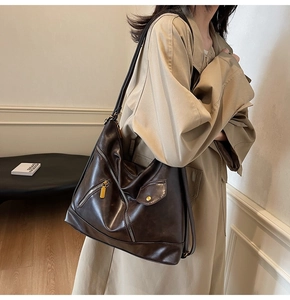 Detail of vintage brown PU leather shoulder bag with gold zippers and multi-pocket design