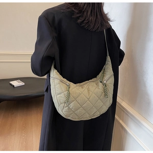 Close-up of sage green quilted hobo bag with diamond texture and rope zipper details