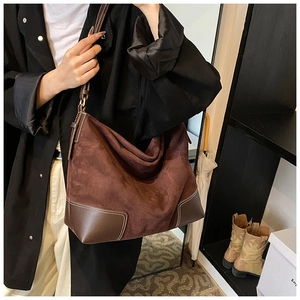 Detail of a brown suede hobo tote bag featuring contrast stitching and adjustable strap