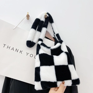 Detail showing the black and white checkered plush fabric and wide strap of the square bag