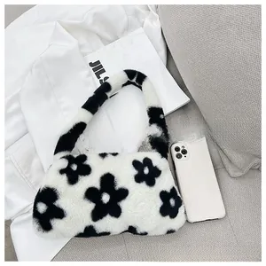 Close-up of plush faux fur underarm bag featuring black and white floral patterns