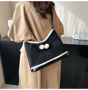 Detail view of black PU tote bag featuring white plush trim and delicate bow embroidery