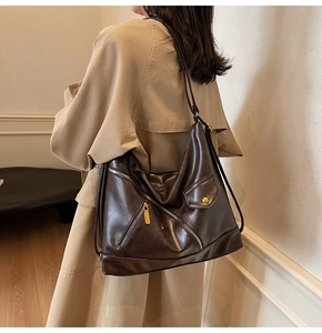 Detail view of brown PU leather tote with metal zippers and decorative flap pocket
