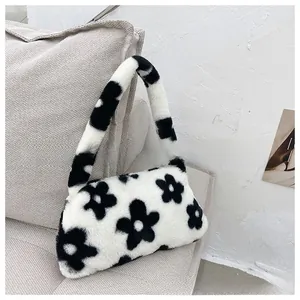 Detail shot of black and white floral faux fur underarm bag texture on a gray sofa