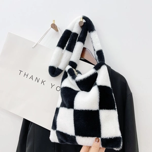 Detail of checkered plush handbag hanging on hook with black blazer outfit styling