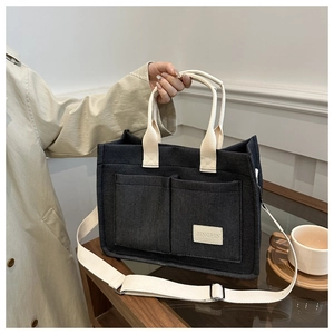 Detailed macro view of dark grey canvas tote bag with adjustable strap and front pockets
