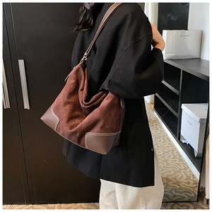 Detail of large brown suede tote bag with contrast stitching and leather trim accents