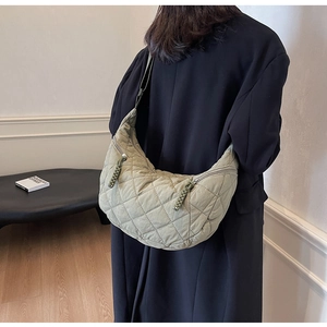 Detail of light green quilted nylon dumpling bag showing braided zipper and crescent shape