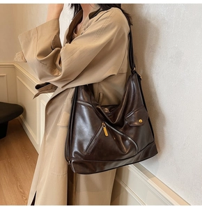 Detail view of coffee PU leather shoulder bag featuring diagonal zipper and flap pocket