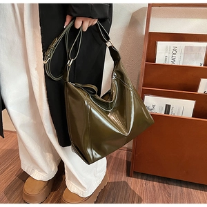 Gros plan d'un sac à bandoulière en cuir verni vert olive avec une finition brillante