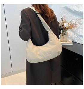 Détail du sac croissant en nylon matelassé beige avec bandoulière noire réglable et boucle