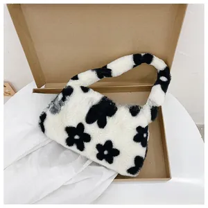 Close-up of plush white shoulder bag with black flower prints in a shipping box