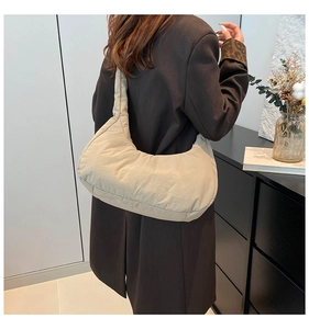 Close-up of beige quilted puffy shoulder bag showing soft padding and crescent shape