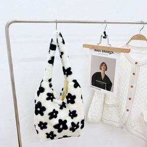 Close-up of fluffy plush shoulder bag with black floral embroidery on white faux fur