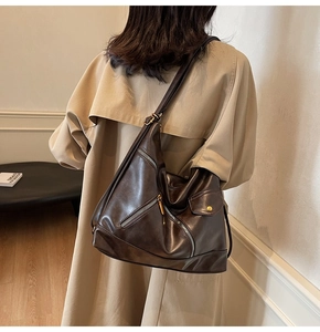 Detail view of dark brown PU leather tote with decorative zippers and gold buckle