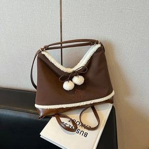 Brown faux leather shoulder bag with white fleece trim and decorative bow pendant