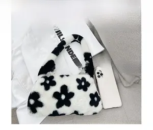 Gros plan d'un sac à bandoulière en peluche noir et blanc aux motifs floraux