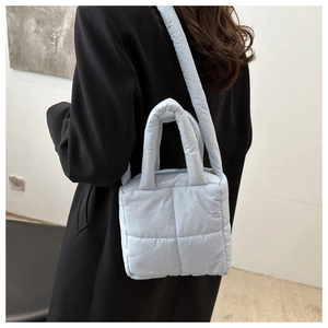 Detail of light blue quilted nylon shoulder bag with thick handles and adjustable strap