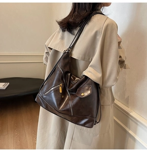 Detail view of deep brown faux leather crossbody bag with multiple zippers and buckles
