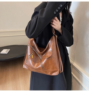 Detail of vintage brown PU leather hobo bag with oily texture and metal zipper accents