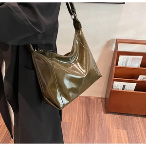Détail d'un sac cabas en cuir PU brillant vert foncé sur mannequin avec fini miroir