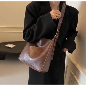 Detail of vintage brown PU leather bucket bag with wide strap and metallic eyelets