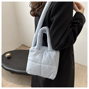 Detail of light blue quilted tote bag with soft padded handle and square puffer pattern
