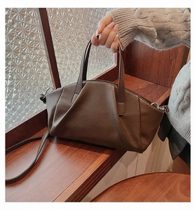 Detail of dark brown pleated PU leather handbag with silver hardware and adjustable strap