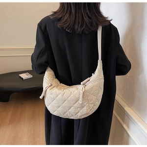 Rear view of a beige quilted moon bag worn with a black coat, showing the fabric texture
