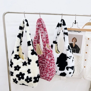 Plush tote bags in floral, pink leopard, and cow prints hanging on a minimalist display