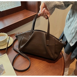 Detailed view of dark brown pleated PU leather handbag with adjustable strap in cafe setting