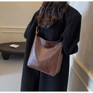 Detail of vintage brown leather tote bag with natural oil wax texture and brass hardware
