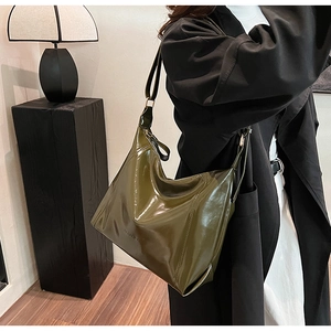 Sac Hobo en similicuir vert foncé brillant porté par un mannequin pour un look fluide