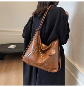 Detail of vintage brown PU leather shoulder bag featuring metal zippers and flap pocket