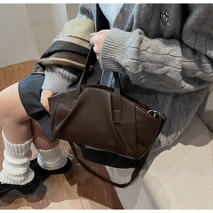 Detailed close-up of dark brown PU leather handbag with elegant pleated design and texture