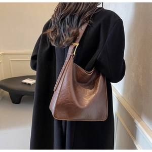 Detail of adjustable wide shoulder strap with gold eyelets on a vintage brown tote bag