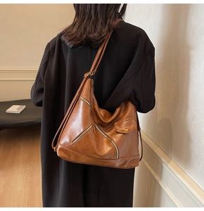 Detail view of vintage brown leather shoulder bag with metallic zippers and cargo style flap
