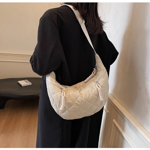 Detail of a beige quilted crescent shoulder bag showing菱格 embroidery and fabric texture