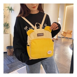 Detail of yellow corduroy mini backpack with cute bear ears and text patch on front