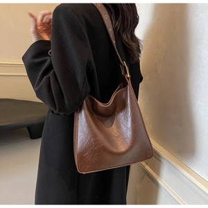 Detail view of a vintage brown leather hobo shoulder bag with adjustable gold buckle strap