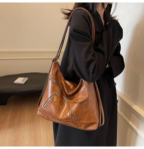 Close-up of vintage brown PU leather handbag with dual functional zippers and metal hardware