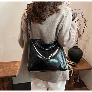 Détail d'un sac à bandoulière noir en cuir verni brillant avec logo CLEAROK embossé