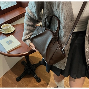 Detail of dark brown pleated PU leather bag shown in a warm indoor cafe setting